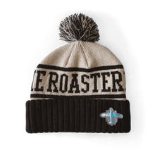 Load image into Gallery viewer, Knit Pom Pom Beanie featuring The Roaster text design in black and white with ribbed cuff, topped with a fluffy striped pom pom. Small airplane emblem on front. Classic winter hat in neutral colors perfect for cold weather.
