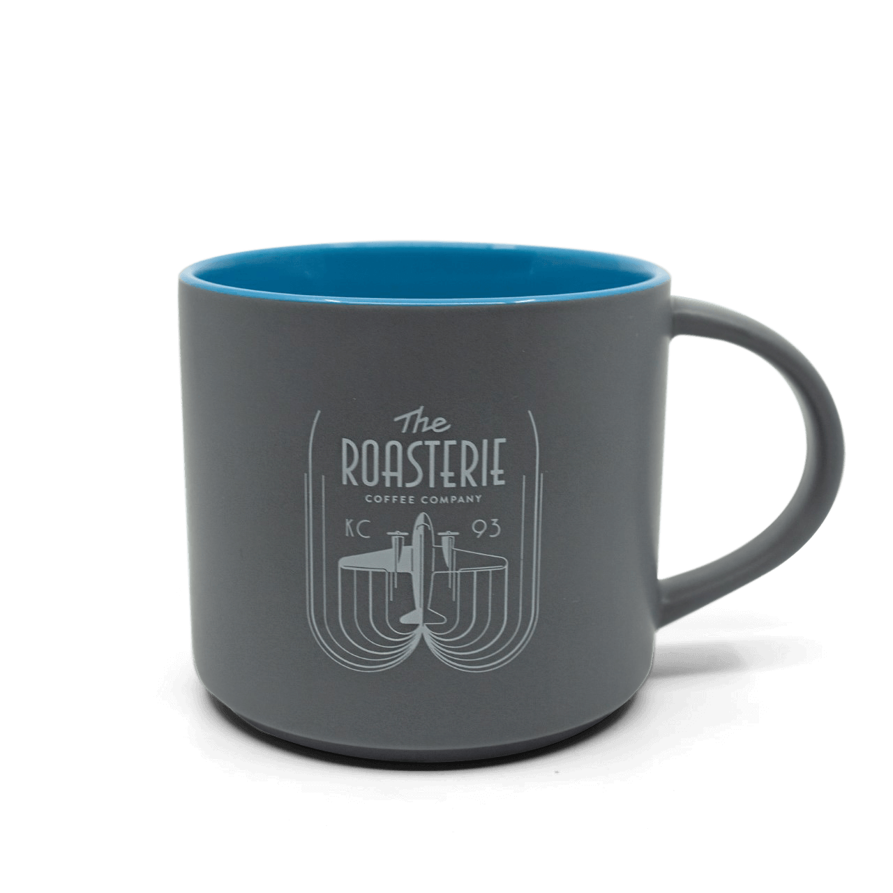 Roasterie DC-3 Gray Blue Mug featuring a matte gray exterior with bright blue interior, showcasing an elegant engraved vintage-style DC-3 airplane logo and curved line design. Ceramic coffee mug with thick walls and comfortable handle.