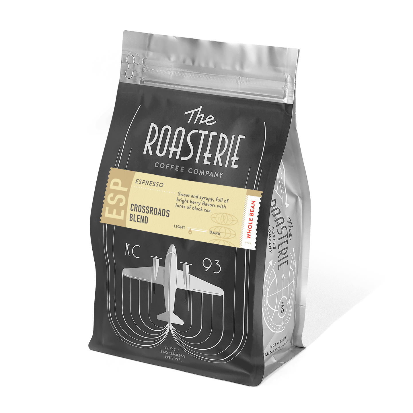 A black coffee bag of Crossroads Espresso by The Roasterie featuring an art deco-style airplane design in silver, with a gold label highlighting the blend name and tasting notes on a resealable package.